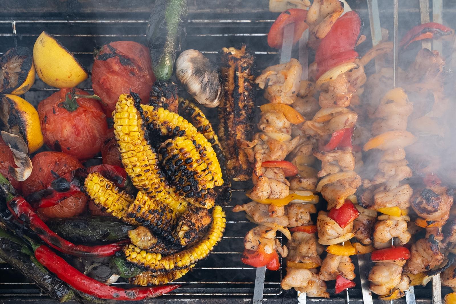 Vegetables and skewers cooking over a grill